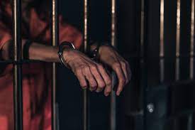 handcuffed man behind bars